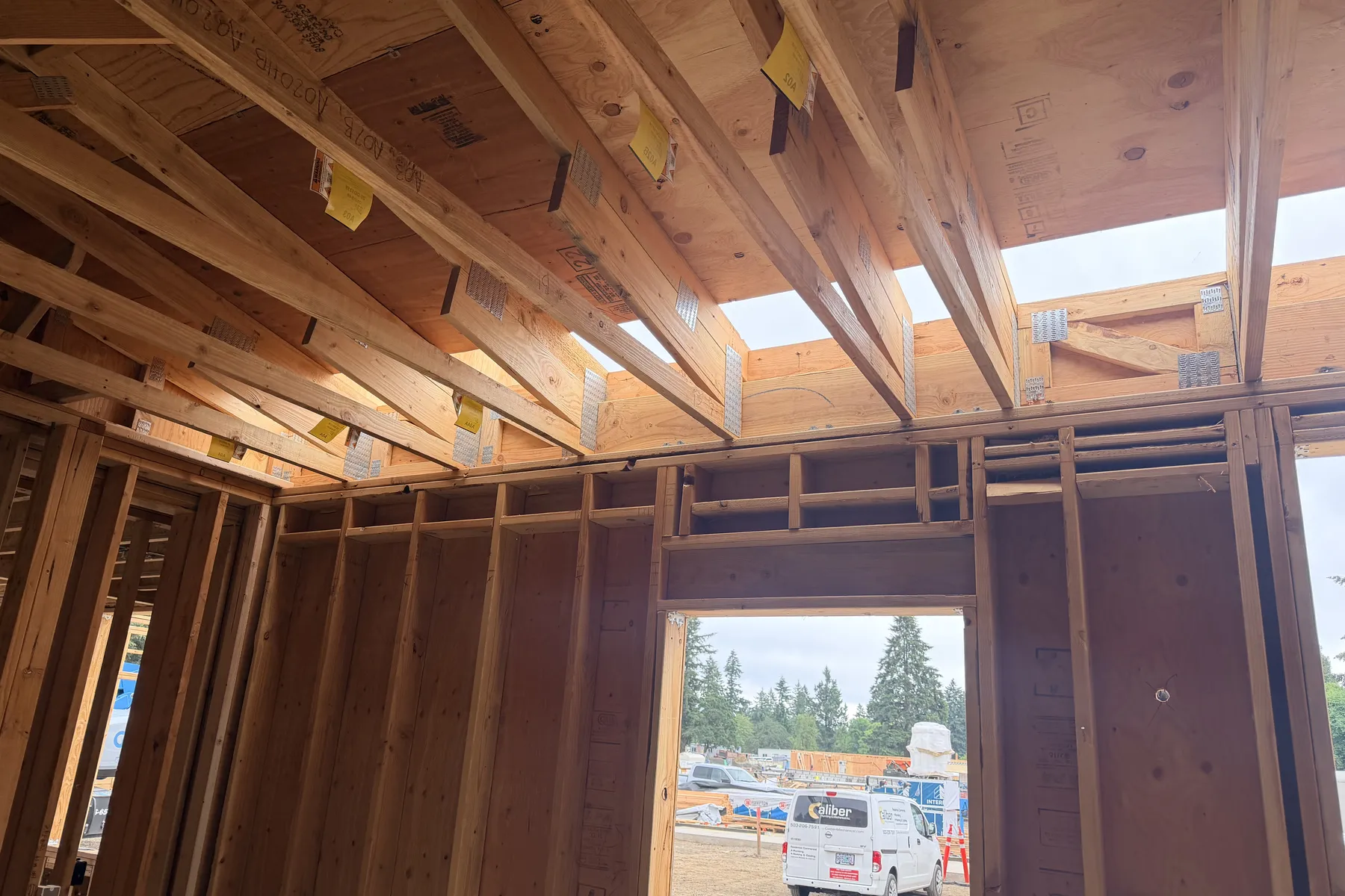 Interior view of ceiling joists on metal hangers above sheathed stud walls