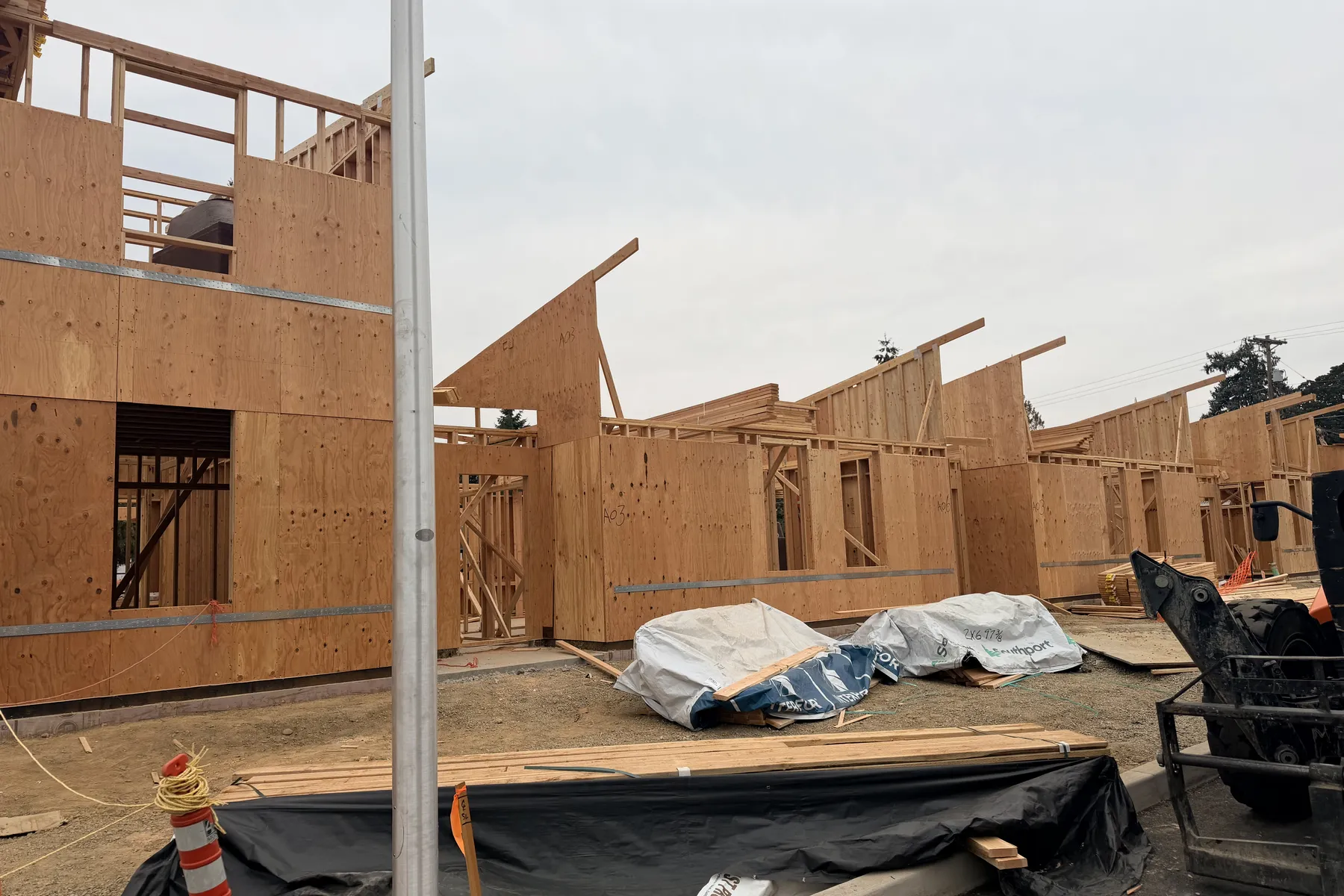 Roof framing and sheathed walls going up across a row of cottage buildings