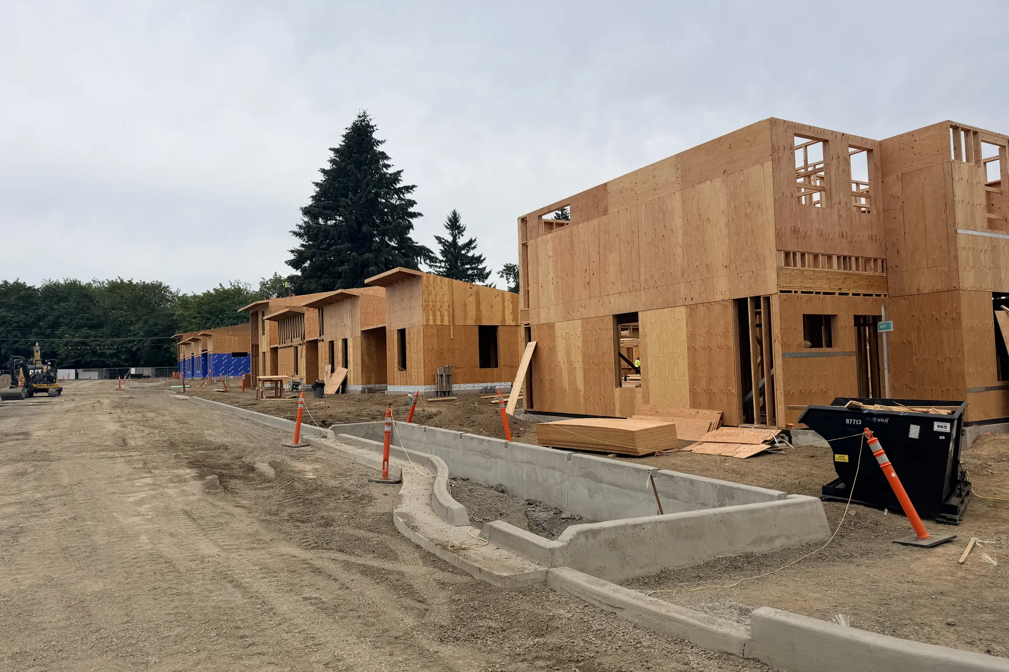 Sheathed two-story wood-framed cottage buildings lining a new street at Park Place in Oregon City