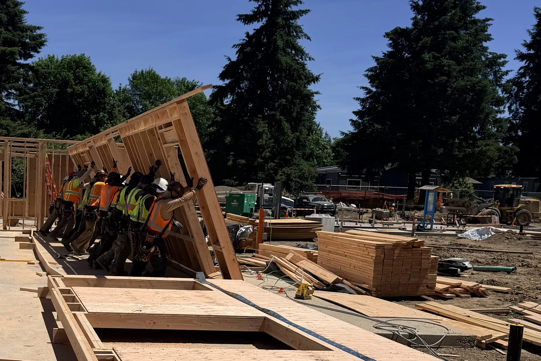Framing crew raising a wood wall panel on a slab at Park Place
